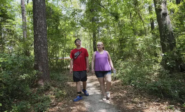 Cayden and his mother Robyn Gillespie walk in a county park Saturday, April 26, 2025, in Gainesville, Fla. (AP Photo/Marta Lavandier)
