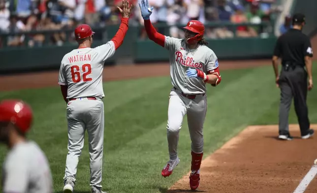 Philadelphia Phillies' Alec Bohm, right, celebrates his three-run home run with third base coach Dusty Wathan (62) as he rounds the bases during the second inning of a baseball game against the Washington Nationals, Sunday, Aug. 17, 2025, in Washington. (AP Photo/Nick Wass)