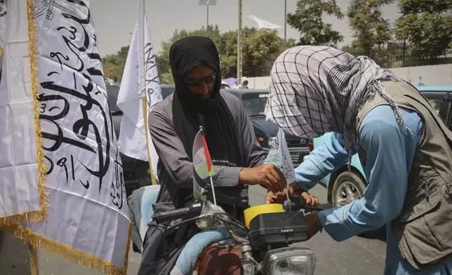 A man decorates his motorcycle with Taliban and Palestinian flags ahead of celebrations marking the fourth anniversary of the US withdraw from Afghanistan and the start of the Taliban rule in Kabul, Afghanistan, Thursday Aug. 14 , 2025. (AP Photo/Siddiqullah Alizai)