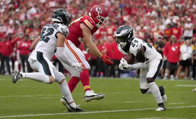 Philadelphia Eagles safety Andrew Mukuba (24) intercepts a pass intended for Kansas City Chiefs tight end Travis Kelce, center, as Eagles safety Reed Blankenship (32) watches during the second half of an NFL football game Sunday, Sept. 14, 2025, in Kansas City, Mo. (AP Photo/Charlie Riedel)