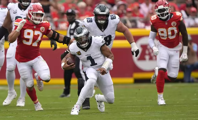 Philadelphia Eagles quarterback Jalen Hurts (1) scrambles as Kansas City Chiefs defensive end Ashton Gillotte (97) and defensive end Charles Omenihu (90) give chase during the first half of an NFL football game Sunday, Sept. 14, 2025, in Kansas City, Mo. (AP Photo/Charlie Riedel)