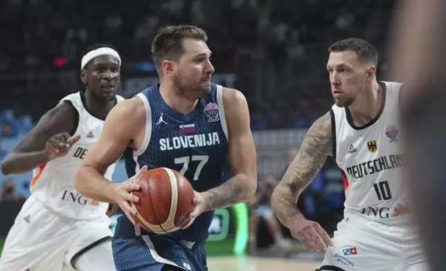 Slovenia's Luka Doncic, centre, Germany's Daniel Theis, right, during the Eurobasket, European Basketball Championship quarter final match between Germany and Slovenia at the Riga Arena in Riga, Latvia, Wednesday, Sept. 10, 2025. (AP Photo/Sergei Grits)