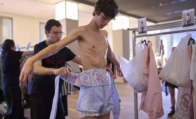 A model is being dressed by an assistant backstage at the brand's show during Fashion Week in Madrid, Spain, Wednesday, Sept. 17, 2025. (AP Photo/Manu Fernandez)