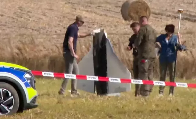 In this image made from video, police and military police officers secure parts of an object shot down by Polish authorities at a site in Wohyn, Poland, Wednesday, Sept. 10, 2025. (AP Photo/Rafal Niedzielski)