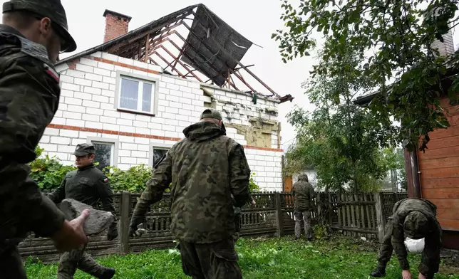 Territorial defense officers pick up debris from the destroyed roof of a house, in Wyryki, Poland, Thursday, Sept. 11, 2025, after Russian drones violated Polish airspace. (AP Photo/Czarek Sokolowski)