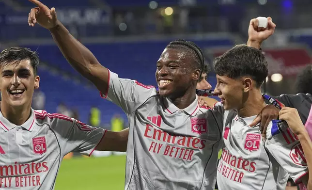 Lyon's Khalis Merah, right, and Lyon's Enzo Molebe, centre, celebrate after the French League One soccer match between Olympique Lyon and Angers at Groupama stadium in Decines, outside Lyon, France, Friday, Sept. 19, 2025. (AP Photo/Laurent Cipriani)
