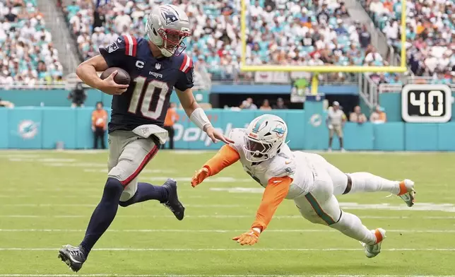 New England Patriots' Drake Maye gets past Miami Dolphins' Matthew Judon for a touchdown run during the second half of an NFL football game Sunday, Sept. 14, 2025, in Miami Gardens, Fla. (AP Photo/Rebecca Blackwell)