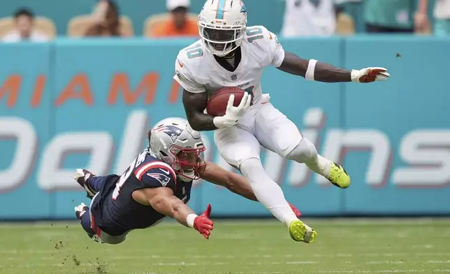 Miami Dolphins' Tyreek Hill gets past New England Patriots' Mack Hollins on a punt return during the second half of an NFL football game Sunday, Sept. 14, 2025, in Miami Gardens, Fla. (AP Photo/Rebecca Blackwell)