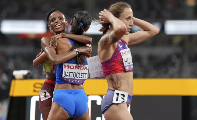 Italy's Nadia Battocletti, bronze, Kenya's Beatrice Chebet, gold, embrace as United States' Shelby Houlihan walks past after the women's 5,000 meters final at the World Athletics Championships in Tokyo, Saturday, Sept. 20, 2025. (AP Photo/Petr David Josek)