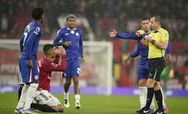 Manchester United's Casemiro, bottom left, receives a second yellow card by a referee during the English Premier League soccer match between Manchester United and Chelsea at the Old Trafford stadium in Manchester, England, Saturday, Sept. 20, 2025. (AP Photo/Dave Thompson)
