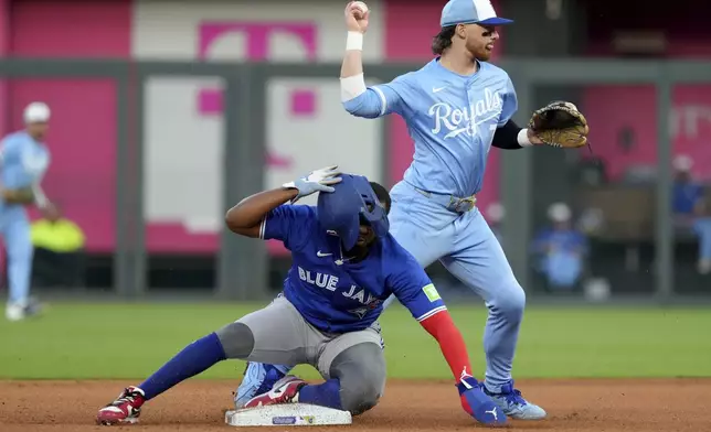Kansas City Royals shortstop Bobby Witt Jr., top, throws to first base past Toronto Blue Jays' Vladimir Guerrero Jr., bottom, to complete a double play in the fourth inning during a baseball game Saturday Sept. 20, 2025, in Kansas City, Mo. (AP Photo/Ed Zurga)