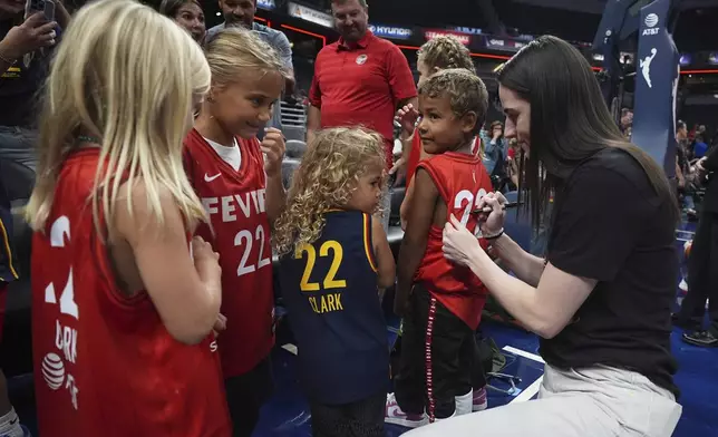Indiana Fever's Caitlin Clark, right, gives autographs to young fans before a WNBA basketball game against the Minnesota Lynx, Friday, Aug. 22, 2025, in Indianapolis. (AP Photo/Darron Cummings)
