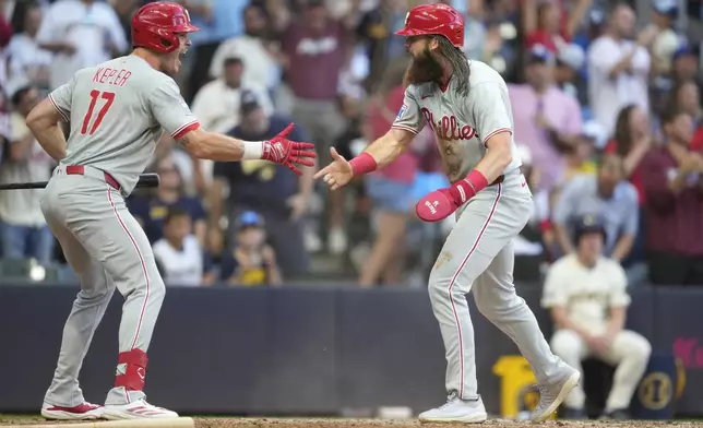 Philadelphia Phillies' Brandon Marsh, right, celebrates with Max Kepler (17) after scoring on an RBI double hit by Harrison Bader during the eighth inning of a baseball game against the Milwaukee Brewers, Monday, Sept. 1, 2025, in Milwaukee. (AP Photo/Kayla Wolf)