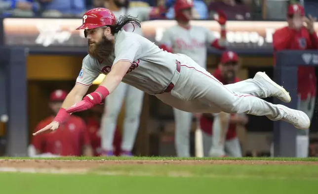 Philadelphia Phillies' Brandon Marsh leaps to score on an RBI double hit by Harrison Bader during the eighth inning of a baseball game against the Milwaukee Brewers, Monday, Sept. 1, 2025, in Milwaukee. (AP Photo/Kayla Wolf)
