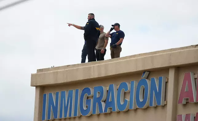 Law enforcement agents look around the roof of an apartment building near the scene of a shooting at a U.S. Immigration and Customs Enforcement office in Dallas on Wednesday, Sept. 24, 2025. (AP Photo/Julio Cortez)