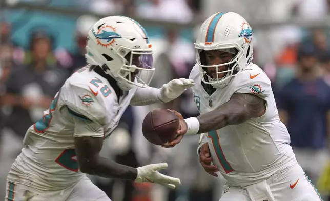 Miami Dolphins' Tua Tagovailoa hands off to De'Von Achane during the second half of an NFL football game against the New England Patriots Sunday, Sept. 14, 2025, in Miami Gardens, Fla. (AP Photo/Rebecca Blackwell)