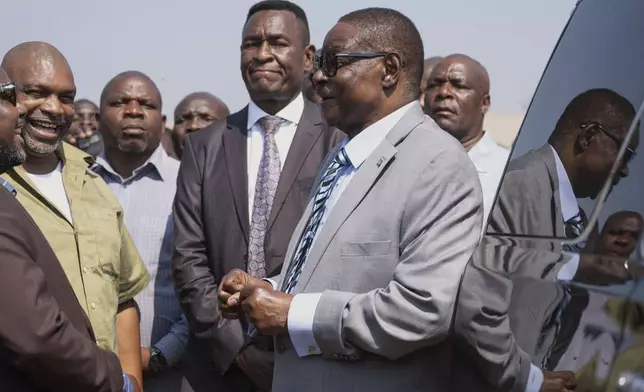 Malawi's presidential candidate, former President Peter Mutharika, right, shares a light moment with officials following casting his vote in Thyolo District, Malawi, Tuesday, Sept. 16, 2025. (AP Photo/Thoko Chikondi)