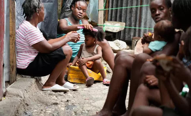 Kettia Jean Charles combs her niece's hair at the Ministry of Public Works, Transport and Communications office, which was converted into a shelter for people displaced by gang violence in Port-au-Prince, Haiti, Wednesday, Sept. 24, 2025. (AP Photo/Odelyn Joseph)