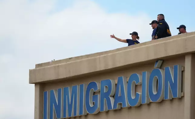 Law enforcement agents look around the roof of a building near the scene of a shooting at a U.S. Immigration and Customs Enforcement office in Dallas on Wednesday, Sept. 24, 2025. (AP Photo/Julio Cortez)