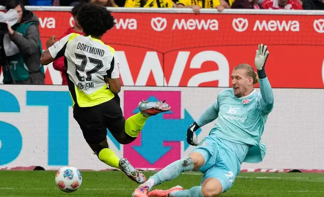 Mainz goalkeeper Robin Zentner, right, makes a tackle on Dortmund's Julian Brandt, during a German Bundesliga soccer match between FSV Mainz 05 and Borussia Dortmund in Mainz, Germany, Saturday, Sept. 27, 2025. (AP Photo/Michael Probst)