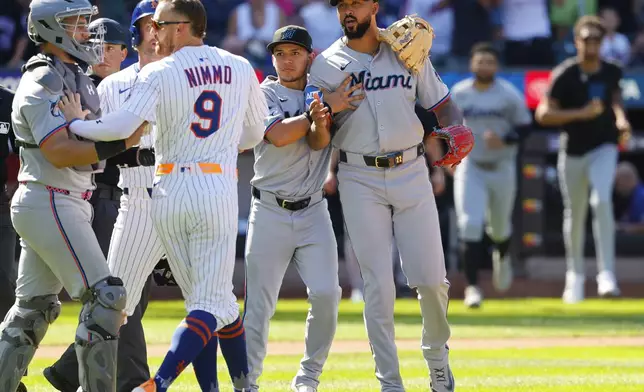 Miami Marlins' Javier Sanoja, second from right, restrains pitcher Sandy Alcantara, right, as the benches emptied after Alcantara hit New York Mets' Mark Vientos with a throw during the seventh inning of a baseball game, Sunday, Aug. 31, 2025, in New York. (AP Photo/Noah K. Murray)