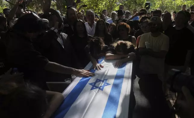 Friends and relatives mourn over the coffin of slain hostage Idan Shtivi, whose body was recovered in an Israeli military operation in the Gaza Strip, during his funeral in Kfar Maas, Israel, Monday, Sept. 1, 2025. (AP Photo/Ariel Schalit)