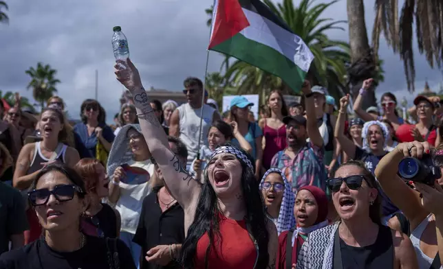 People shout slogans as they bid farewell to activists setting sail on their boats to join a civilian flotilla bound for Gaza, with the aim of breaking the Israeli blockade and delivering humanitarian aid, in Barcelona, Spain, on Sunday, August 31, 2025. (AP Photo/Emilio Morenatti)