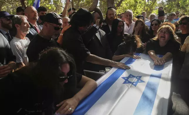 Friends and relatives mourn over the coffin of slain hostage Idan Shtivi, whose body was recovered in an Israeli military operation in the Gaza Strip, during his funeral in Kfar Maas, Israel, Monday, Sept. 1, 2025. (AP Photo/Ariel Schalit)
