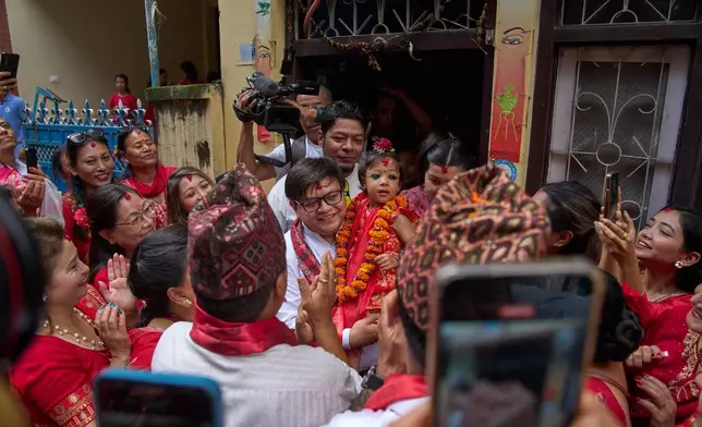 Nepal's newly appointed living goddess, Kumari Aryatara Shakya, is carried by her family member as they get ready to walk towards Kumari Ghar, the temple palace where she will be residing in Kathmandu, Nepal, Tuesday, Sept. 30, 2025. (AP Photo/Niranjan Shrestha)