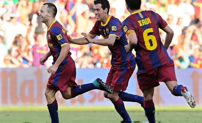 FILE - Barcelona's Andres Iniesta, left, is congratulated by teammates Sergio Busquets, center, and Xavi Hernandez after scoring against Racing de Santander during their Spanish La Liga soccer match at El Sardinero stadium in Santander, northern Spain Sunday Aug. 29, 2010. (AP Photo/Alvaro Barrientos, File)