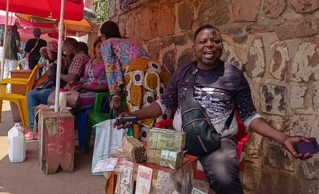 A currency exchanger buys perforated notes that are rejected by people in Bukavu, Democratic Republic of the Congo, Friday, Aug 29, 2025. (AP Photo)