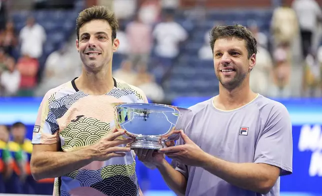 Marcel Granollers, of Spain, left, and Horacio Zeballos, of Argentina, hold the championship trophy after defeating Joe Salisbury, of Great Britain, and Neal Skupski, of Great Britain, in the men's doubles final of the U.S. Open tennis championships, Saturday, Sept. 6, 2025, in New York. (AP Photo/Yuki Iwamura)