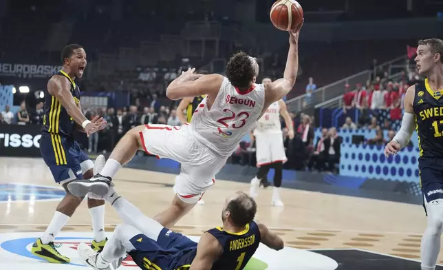 Sweden's Denzel Andersson, bottom, falls after colliding with Turkey's Alperen Sengun, centre, during the Eurobasket, European Basketball Championship round of 16 match between Turkey and Sweden at the Riga Arena in Riga, Latvia, Saturday, Sept. 6, 2025. (AP Photo/Sergei Grits)