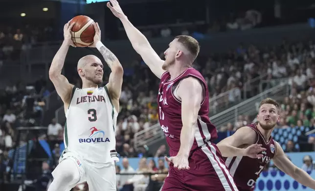 Lithuania's Arnas Velicka, left, tries to shoot while defended by Latvia's Rolands Smits during the Eurobasket, European Basketball Championship round of 16 match between Lithuania and Latvia at the Riga Arena in Riga, Latvia, Saturday, Sept. 6, 2025. (AP Photo/Sergei Grits)