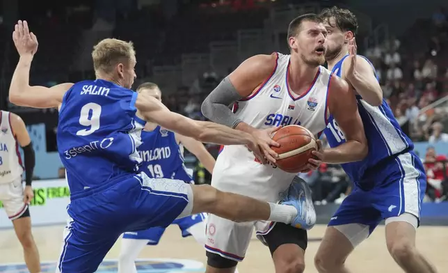 Serbia's Nikola Jokic drives between Finland's Sasu Salin, left, and Finland's Mikael Jantunen during the Eurobasket, European Basketball Championship round of 16 match between Serbia and Finland at the Riga Arena in Riga, Latvia, Saturday, Sept. 6, 2025. (AP Photo/Sergei Grits)
