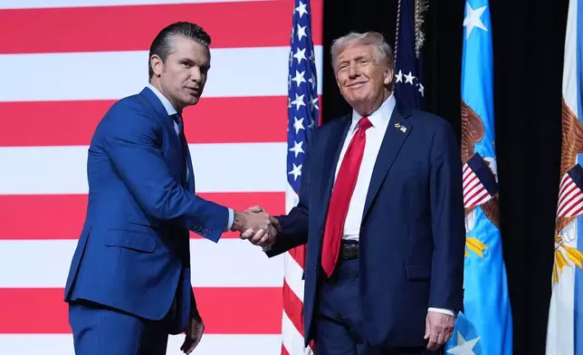 President Donald Trump is greeted by Secretary of Defense Pete Hegseth before speaking to a gathering of top U.S. military commanders at Marine Corps Base Quantico, Tuesday, Sept. 30, 2025, in Quantico, Va. (AP Photo/Evan Vucci)