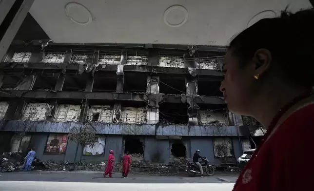 Nepalese people inspect a building of Bhatbhatini shopping center vandalized during anti-corruption protests protests sparked by a short-lived social media ban in Kathmandu, Nepal, Saturday, Sept. 13, 2025. (AP Photo/Niranjan Shrestha)