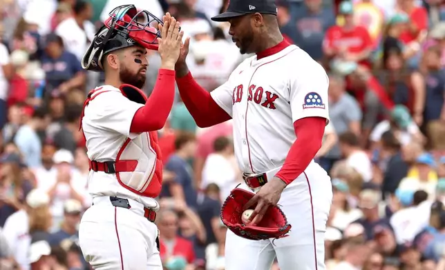 Boston Red Sox catcher Connor Wong, left, and pitcher Aroldis Chapman, right, high-five after a baseball game against the Cleveland Guardians, Monday, Sept. 1, 2025, in Boston. (AP Photo/Mark Stockwell)