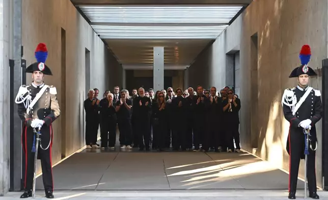 Staff of Giorgio Armani Spa gather outside the Armani/Teatro in Milan, northern Italy, as the hearse with the casket of designer Giorgio Armani, who died Thursday at age 91, leaves, Sunday, Sept. 7, 2025. (AP Photo/Nicola Marfisi)