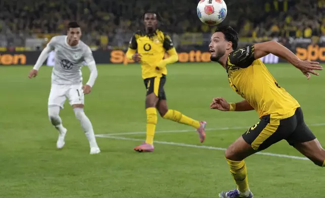 Dortmund's Ramy Bensebaini, right, heads the ball during the German Bundesliga soccer match between Borussia Dortmund and VfL Wolfsburg in Dortmund, Germany, Sunday, Sept. 21, 2025. (AP Photo/Martin Meissner)
