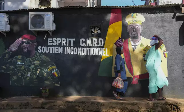 CORRECTS TITLE OF MILITARY LEADER People walk past a mural showing Guinea's interim president, Gen. Mamadi Doumbouya, ahead of the constitutional referendum in Conakry, Guinea, Wednesday, Sept. 17, 2025. (AP Photo/Misper Apawu)