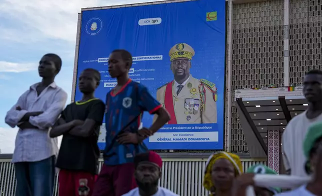 CORRECTS TITLE OF MILITARY LEADER People stand in front of a billboard showing Guinea's interim President, Gen. Mamadi Doumbouya, ahead of the constitutional referendum in Conakry, Guinea, Thursday, Sept. 18, 2025. (AP Photo/Misper Apawu)