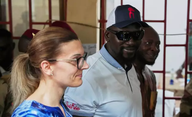 Guinea's interim President, Gen. Mamadi Doumbouya, departs with his wife after casting his vote in the constitutional referendum in Conakry, Guinea, Sunday, Sept. 21, 2025 (AP Photo/Misper Apawu)