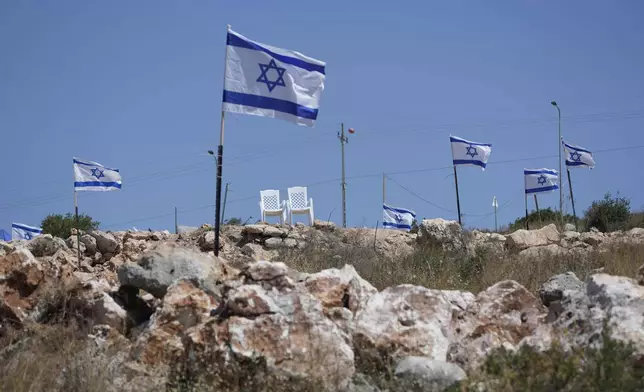 FILE - Israeli flags flutter on top of a hill that is adjacent to Palestinian properties that were under attack by Israeli settlers overnight, leaving several burnt vehicles and damaged homes, residents said, in the West Bank village of Bruqin, near Salfit, Friday, May 23, 2025. (AP Photo/Nasser Nasser, File)