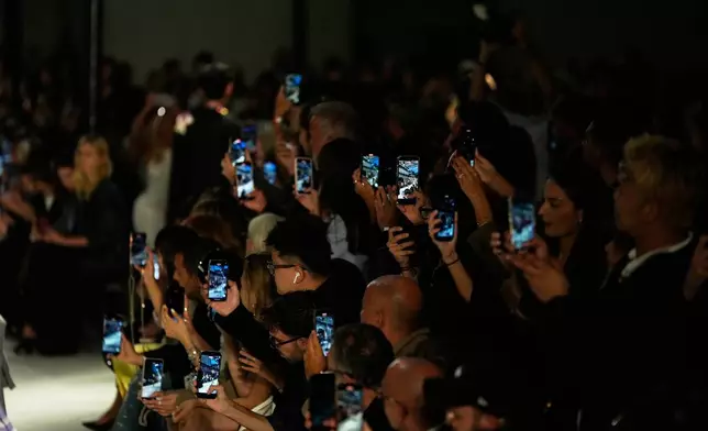 Guests use their smartphones to film and photograph models as they wear creations part of the N21 women's Spring-Summer 2026 collection, that was presented in Milan, Italy, Wednesday, Sept. 24, 2025. (AP Photo/Luca Bruno).