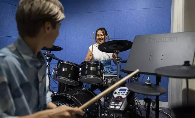 Same-sex partners Jaedyn Yu, left, and Gloria Tsang play drums in a band room in Hong Kong, Sunday, Aug. 24, 2025. (AP Photo/Chan Long Hei)
