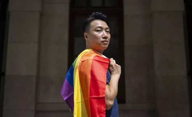 Jimmy Sham, gay rights activist and former pro-democracy district councillor, holds rainbow flag as he poses for photographs in front of the court of final appeal in Hong Kong, Sunday, Aug. 24, 2025. (AP Photo/Chan Long Hei)