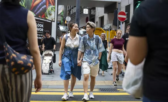 Same-sex partners Jaedyn Yu, right and Gloria Tsang cross the road in Hong Kong, Sunday, Aug. 24, 2025. (AP Photo/Chan Long Hei)