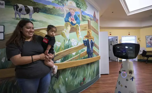 Robin the Robot, developed by Expper Technologies, interacts with Erica Ruiz and her daughter, Valentina, at the HealthBridge Orange Specialty Pediatric Hospital in Orange, Calif., on Friday, Sept. 12, 2025. (AP Photo/Damian Dovarganes)