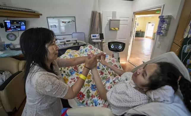 Cara Nguyen with her daughter, Kathy, 18, are visited by Robin the Robot at the HealthBridge Orange Specialty Pediatric Hospital in Orange, Calif., on Friday, Sept. 12, 2025.(AP Photo/Damian Dovarganes)